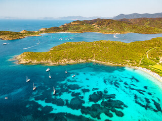 Panoramic drone view of the coastline of a perfectly clear sea on the Italian island of Sardinia. Turquoise sea with white beaches