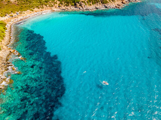 Small boat near the beach with turquoise clear water. The most beautiful sea in Italy. Sardinia Italy