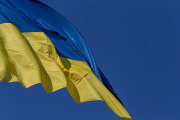 waved flag of Ukraine against clear blue sky