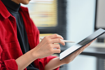 Closeup view of modern business man holding paper cup and using digital tablet at office desk