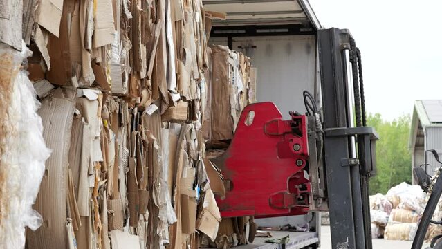 Fork lift at recycling center unloading bale of cardboard, ready for processing.