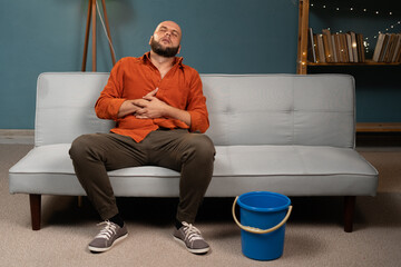 Sick man suffering from sick stomach and vomiting at home on the couch