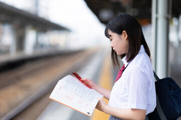 駅のホームで勉強する高校生