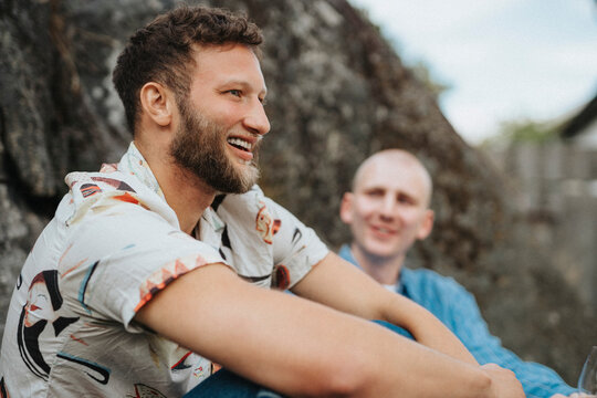 Happy young man with beard sitting with friend