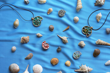 Fototapeta na wymiar pendants in the form of shells on a blue background with marine attributes