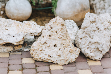 An old uneven mountain stone, a cobblestone in holes lies on a tile. Photography, nature.