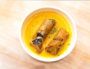 Morcilla sausage rolls with orange sauce on a wooden table.