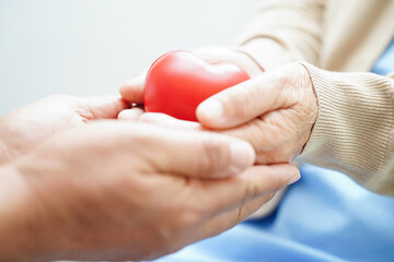 Asian elder senior woman patient holding red heart in hospital. - obrazy, fototapety, plakaty