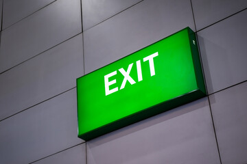 A green fire escape sign is stuck on the ceiling. Green exit sign at the exit door