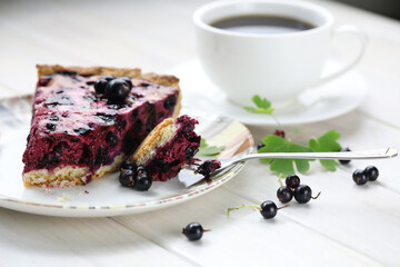 Baked pie with season berries and cup of coffee on wooden background
