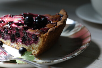 Baked pie with season berries and cup of coffee on wooden background