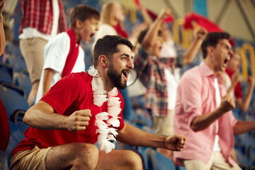 Young emotional people, sport fans attending live football match to cheer up favourite team. Sport...