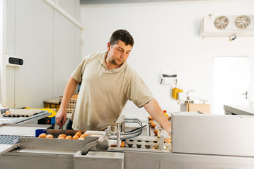Focused young man standing near egg grading machine