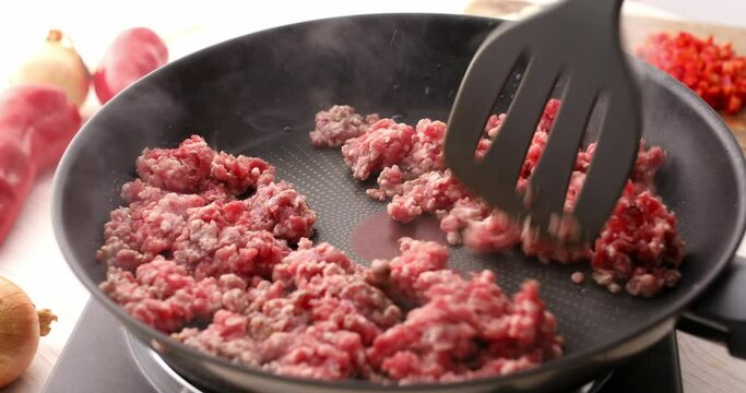 Man frying minced meat in a frying pan stirring with a spatula. Cooking bolognese sauce. Food preparation in the kitchen. A series of footage to visualize the recipe.