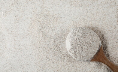 Pile of integral barley flour in wooden spoon, top view 