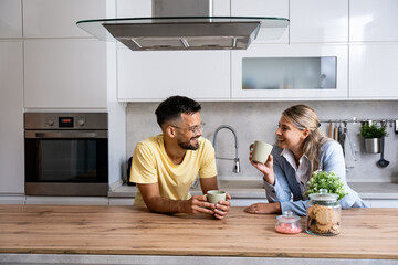 Young man made first coffee for his girlfriend in formal wear who goes to work and they drink it together in the morning in the kitchen while discussing what they will do when she comes home from work