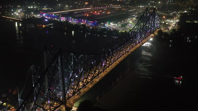 Aerial view of architectural landmark Howrah bridge or Rabindra Setu over the Hooghly River at night in Kolkata, West Bengal, India.