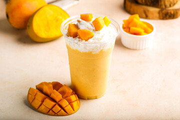 Mango milkshake with cream and raw fruit slice served in glass isolated on table top view healthy morning drink
