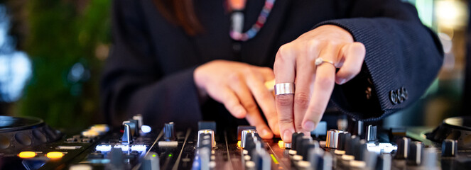 woman DJ Hands creating and regulating music on dj console mixer in concert
