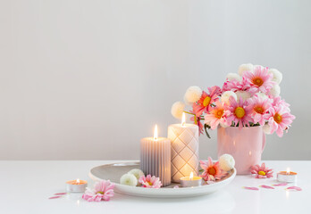 burning candles and pink and white  chrysanthemums in white interior