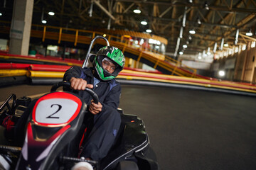 Fototapeta na wymiar go cart speed drive, african american driver in helmet on circuit, karting motorsport concept