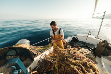 Fisherman fishing in open sea from sail boat
