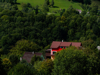 Modern red house in Carpathian mountains forest, Ukraine, Europe. Scenic landscape green meadow spruce trees sunny day Eco Local countryside tourism hiking trails Cottagecore Zakarpattya region travel