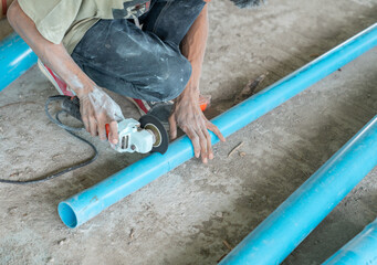 Plumper using electric grinder to cut pvc pipe without gloves.