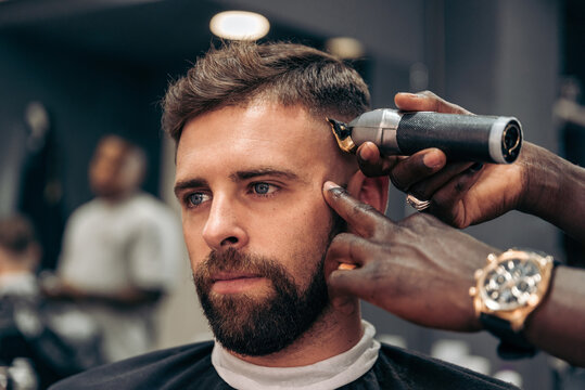 Crop barber trimming hair of male client
