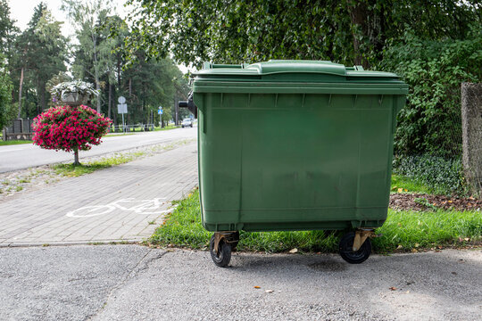 Green garbage container by the side of the street. Copy space