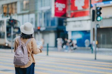 Asian tourist, cute woman with long hair are traveling in Hong Kong along with map and her camera with fun on her holiday,traveler relaxing and enjoying at city and building in Hong Kong.