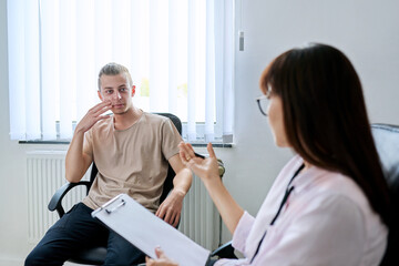 Young male student at therapy meeting with college psychologist counselor