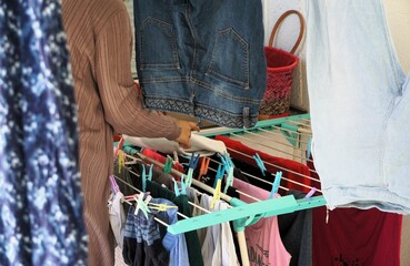 Seitenansicht von junger Frau mit fliederfarbener Strickjacke beim Wäsche aufhängen auf Terrasse...