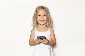 Studio portrait of happy child girl with smartphone in hand isolated on white background.