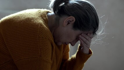 Mature woman struggles from mental bad health at home. Senior lady cries sitting at home. Grey-haired female suffers with depression - Powered by Adobe