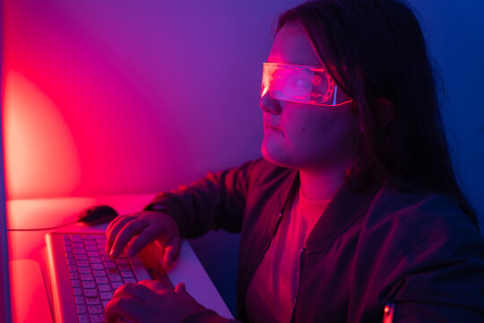 Young girl wearing AR glasses sitting at desk with computer monitor