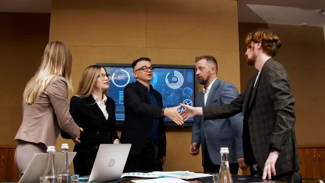 In the meeting room, a team of general directors are talking, finalizing development, shaking hands. Stylish people in a modern conference room.