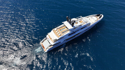 Aerial drone photo of beautiful modern super yacht with wooden deck cruising in low speed deep blue...