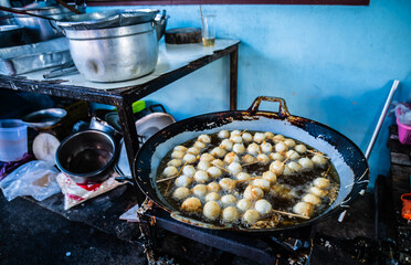 A vendor is frying meatballs to sell in the market at Ban Na Kluea, Pattaya, Thailand