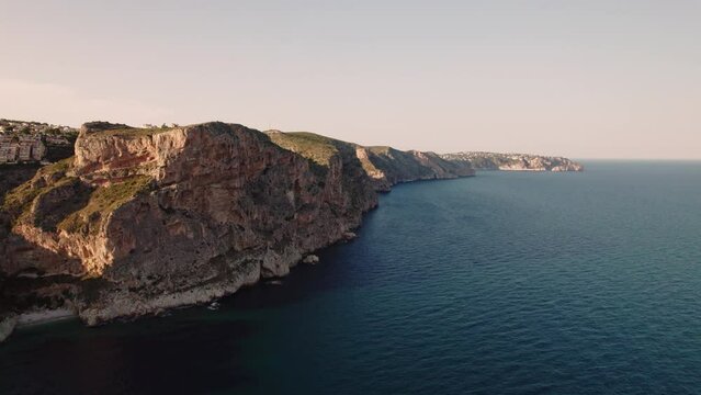 Aerial view of Breathtaking coastal panorama with clear blue sea, rugged cliffs, and the serene tranquility of small holiday houses,  Cala Moraig, Zona Encinas, Cumbre del Sol, Alicante, Spain