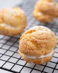 Choux cream, vanilla whipped cream stuffed cake over metal grid