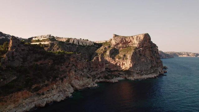 Aerial view of Breathtaking coastal panorama with clear blue sea, rugged cliffs, and the serene tranquility of small holiday houses,  Cala Moraig, Zona Encinas, Cumbre del Sol, Alicante, Spain