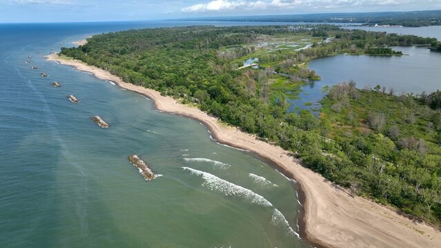 Beautiful sandy beach and coastline of barrier island on Lake Erie Pennsylvania Presque Isle State Park with nature preserve in sunshine on summer day with blue sky and calm waves and surf