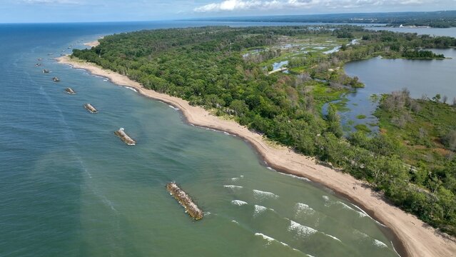 Beautiful sandy beach and coastline of barrier island on Lake Erie Pennsylvania Presque Isle State Park with nature preserve in sunshine on summer day with blue sky and calm waves and surf