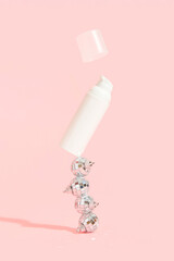 Bottle of cosmetic cream with festive decor on a pink background. Sale concept