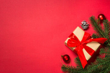 Christmas background with present, fir tree and decorations at red background. Top view with space for your text.
