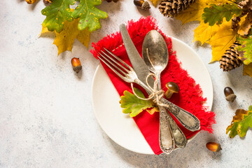 Thanksgiving food concept. Autumn table setting with white plate, silverware and fall decorations at white table. Top view with copy space.