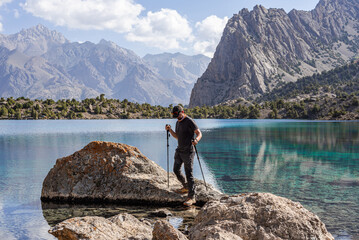 Man hiker exploring mountains lake in Tajikistan - obrazy, fototapety, plakaty