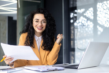 Portrait of a successful woman winner behind a paper work, businesswoman smiling and looking at the...