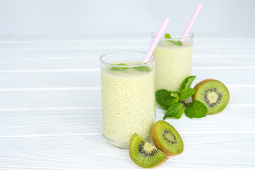 Kiwi yogurt fruit juice smoothie and green kiwi juice drink healthy, delicious taste in a glass for weight loss on a white wooden background.
